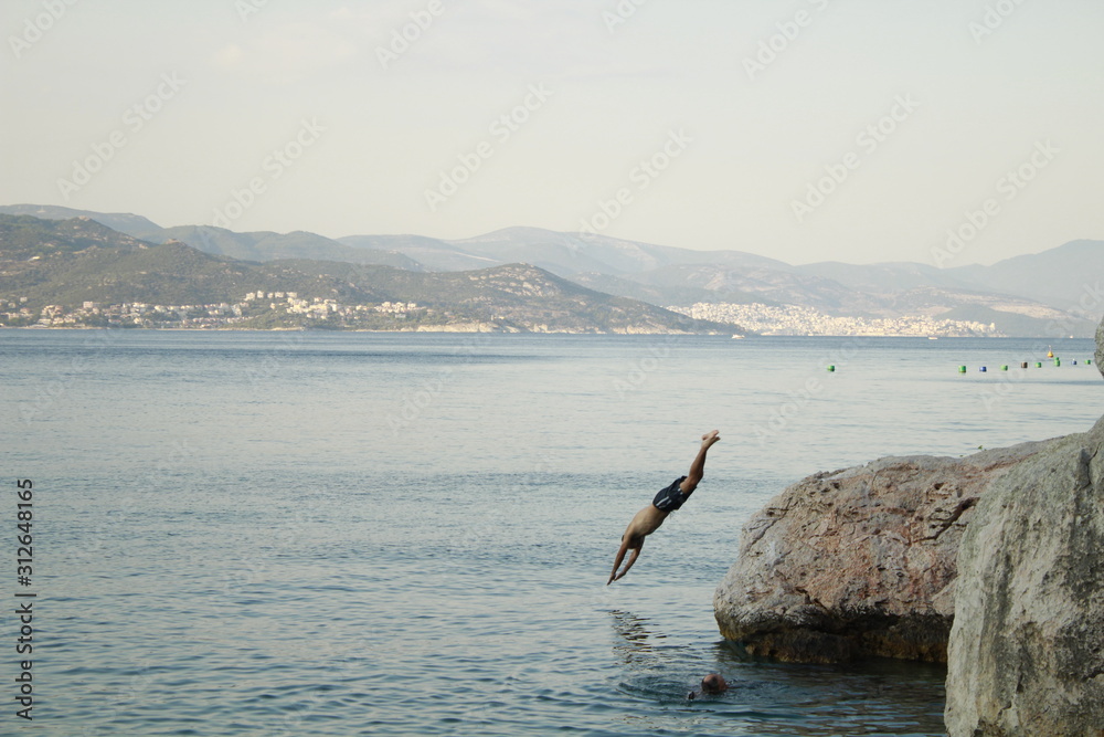 Fototapeta premium Young man diving into the sea from a rock