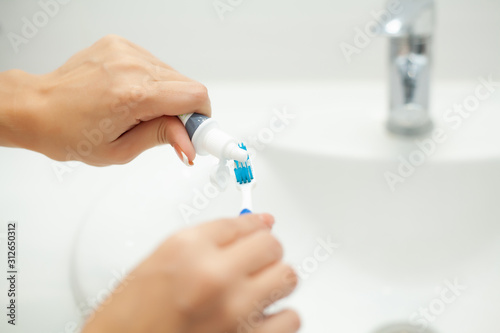 Close up hands woman use toothbrush in light bathroom