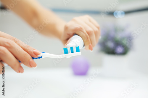 Close up hands woman use toothbrush in light bathroom