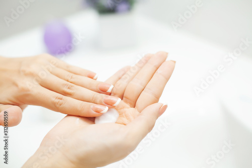 Close up hands use care products in light bathroom