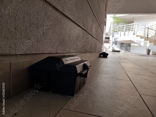 Pest control rat trap which contains poison placed at shady area at a office building