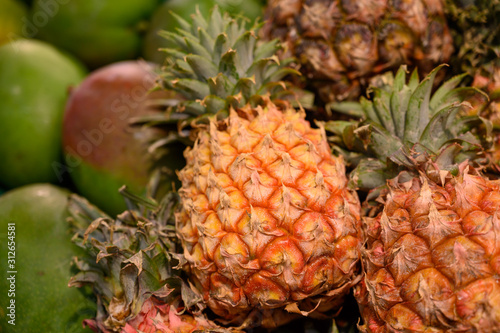 Exotic fruits, fresh ripe sweet pinapples and mango, tropical food background