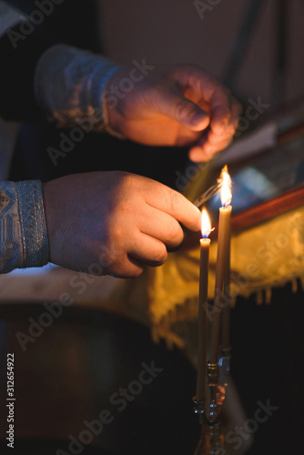 priest holding scissors in candle's fire