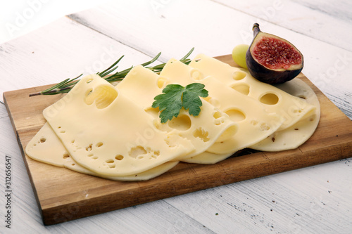 cheese slices on wooden tray with parsley. gauda cheese