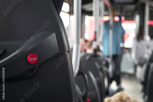 Close up of stop button on public transport bus positioned ont he back of a seat.