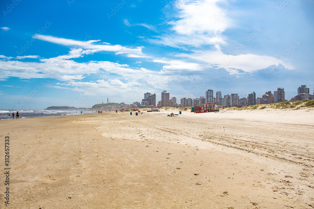 Obraz premium Mar e areia e o céu azul com nuvens na Praia Grande, cidade de Torres, estado do Rio Grande do Sul, Brasil