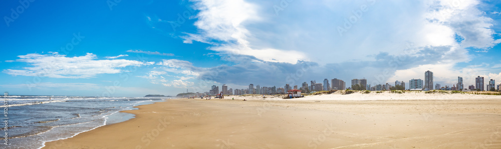 Mar e areia e o céu azul com nuvens na Praia Grande, cidade de Torres, estado do Rio Grande do Sul, Brasil