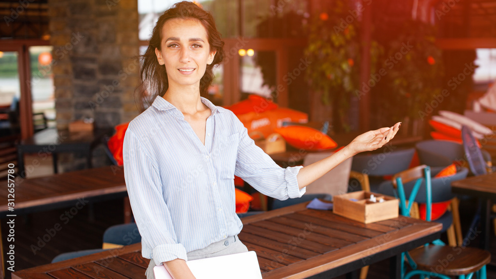 Portrait of female restaurant manager. Businesswoman work with laptop and mobile phone in cafe.