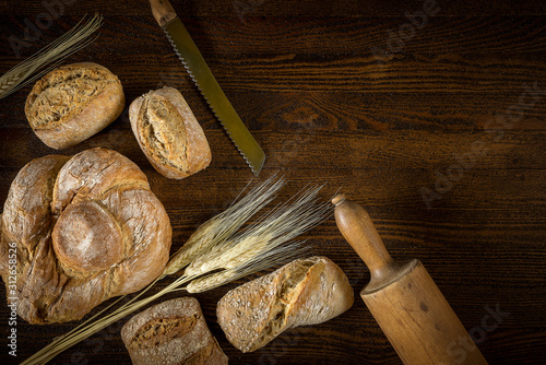 Obraz na płótnie Traditional fresh bread with a blade of wheat on a wooden background. w salonie
