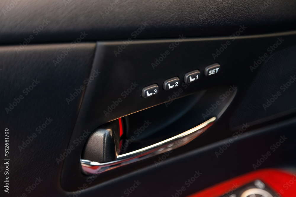 Three-drivers seat memory adjustment buttons for quick tilt adjustment for comfort and convenience with a plastic inset on a black car door. Auto service industry.