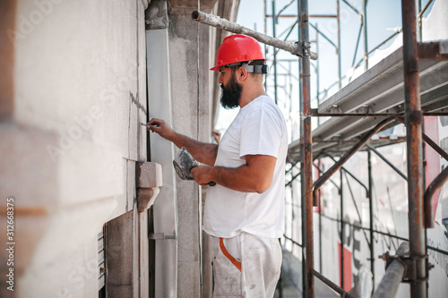 Man worker standing on scaffolding, perform work on the restoration of the facade of the old building. Repairing and renovate © guruXOX