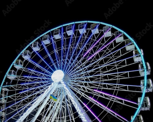 Multi-colored luminous ferris wheel at night