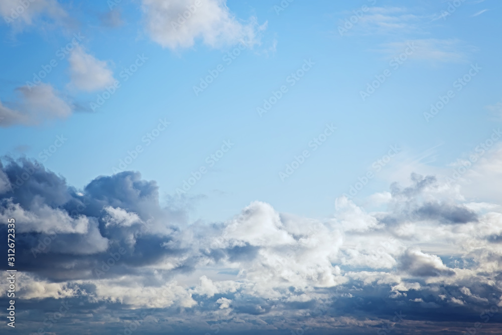 Cumulus white and gray clouds on a blue sky. Beautiful dreamy scene of air clouds on blue sky background.