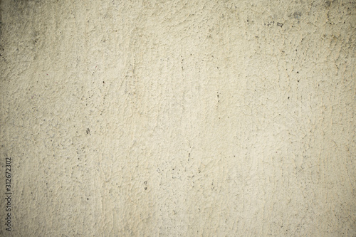 The texture of the concrete wall covered with whitewash with traces of aging.