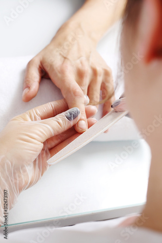 Woman sawing nails at beauty salon. Manicure
