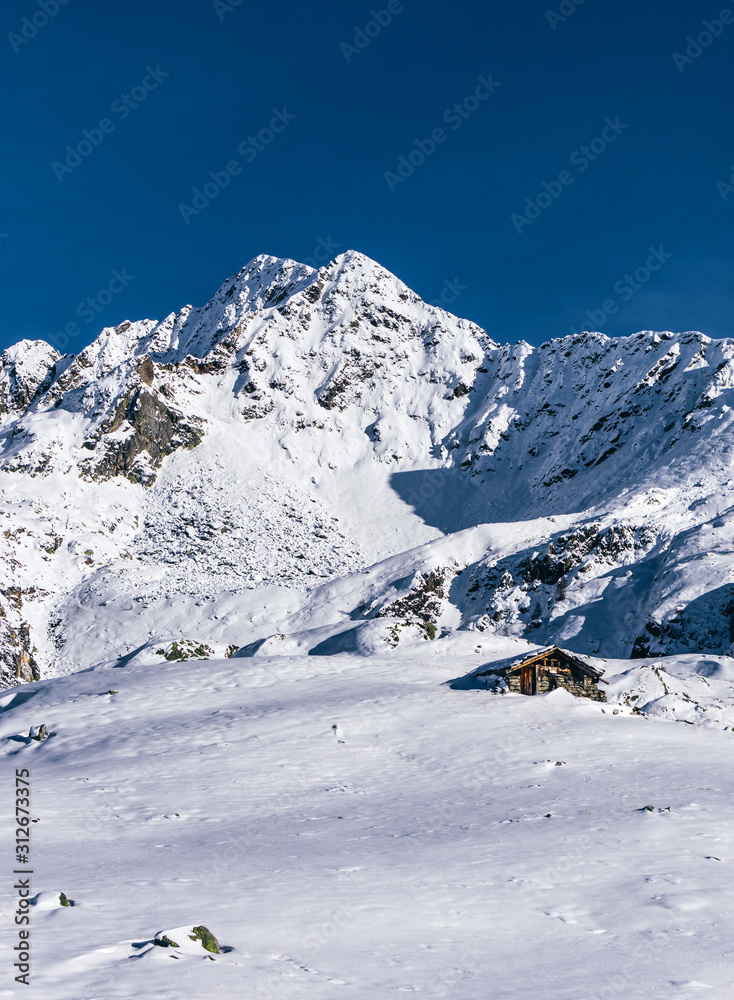 The snowy mountains, the nature and the landscape of the Valtellina after the first snowfall of the season in the Alps, near the town of Tartano, Italy - November 2019.