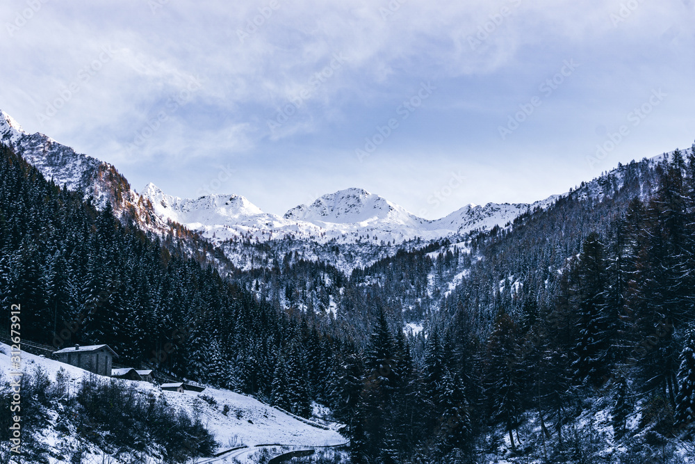 The snowy mountains and the Valtellina landscape at sunset after the first snowfall of the season in the Alps, near the town of Tartano, Italy - November 2019.