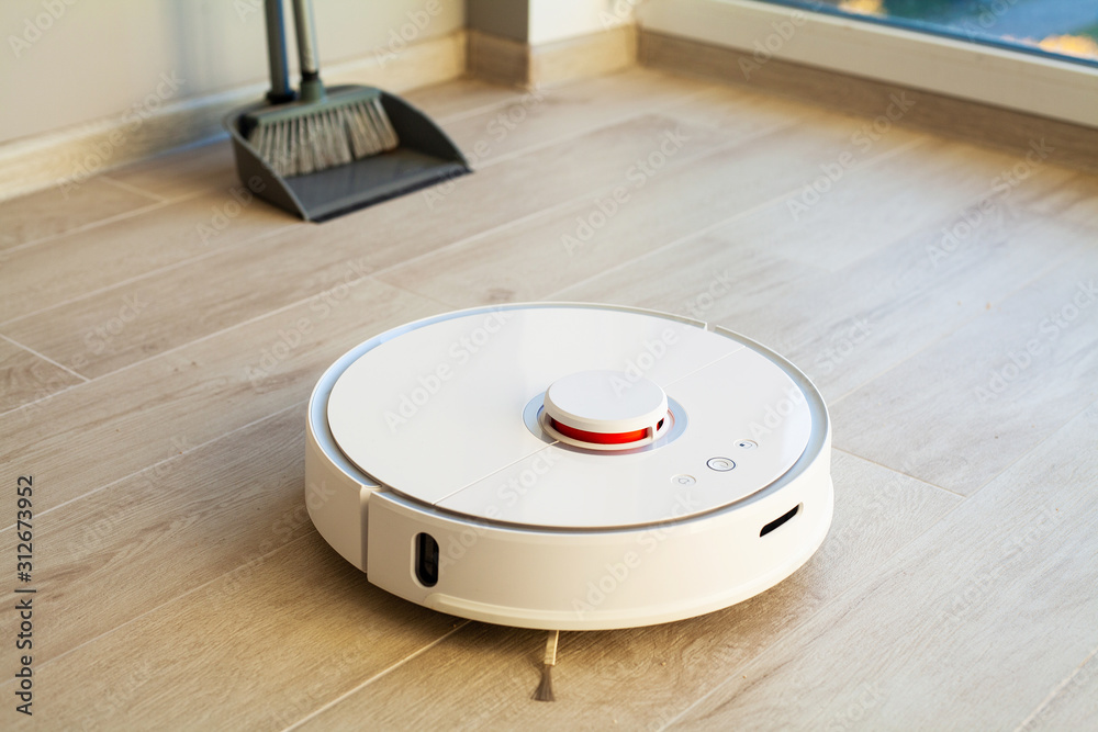 Smart House. Vacuum cleaner robot runs on wood floor in a living room Smart House. Vacuum cleaner robot runs on wood floor in a living room