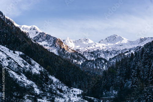 The snowy mountains and the Valtellina landscape at sunset after the first snowfall of the season in the Alps, near the town of Tartano, Italy - November 2019.