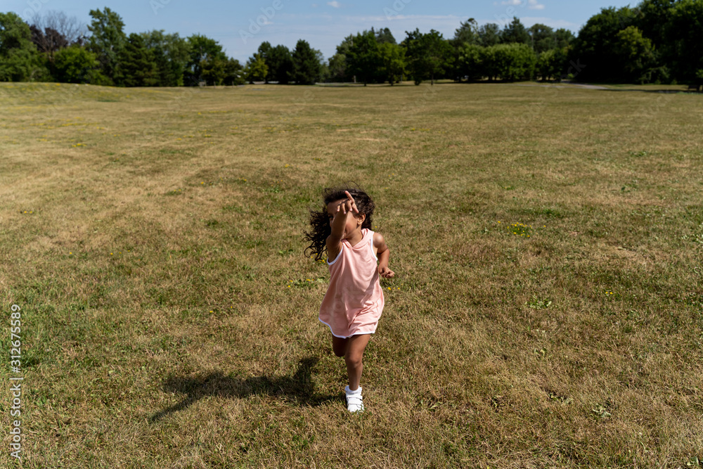 Young girl in pink dress and running in a park seen from behind Young girl in pink dress and running in a park seen from behind