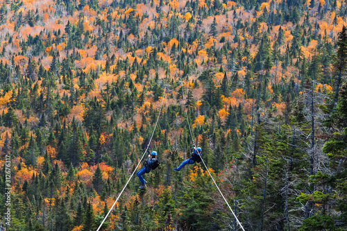 two people sliding down very long and fast zipline during autumn in Stowe, Vermont