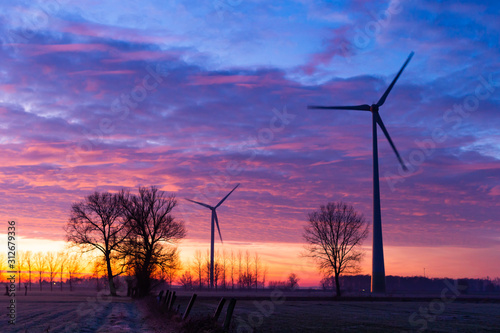 2 windmills in front of colourfull clouds photo