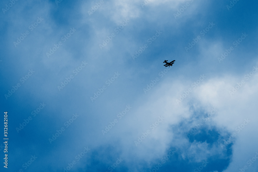 green airplane flying high in a cloudy blue sky. long-range shooting.  toned  in classic blue trendy color of the year 2020