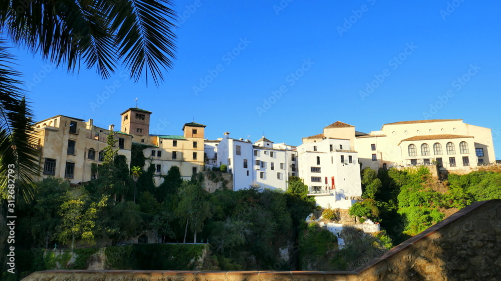 Obraz premium weiße Häuser stehen auf hohem Fels in Ronda über grünen Bäumen