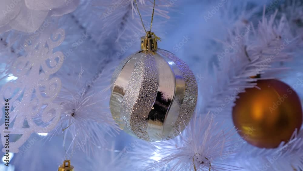 White christmas tree decorated with golden and silver balls. Beautiful  silver and gold Christmas balls and blue garlands on a Christmas tree.