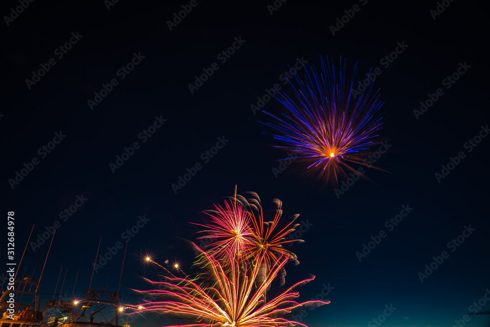 Fireworks celebration of long exposure over a calm fishing wharf