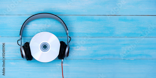 Wired headphones with compact disk on blue pastel background. Retro style, DJ. Top view music concept