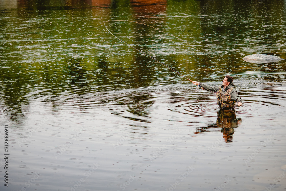 Fisherman using rod fly fishing in river morning standing in water Fisherman using rod fly fishing in river morning standing in water