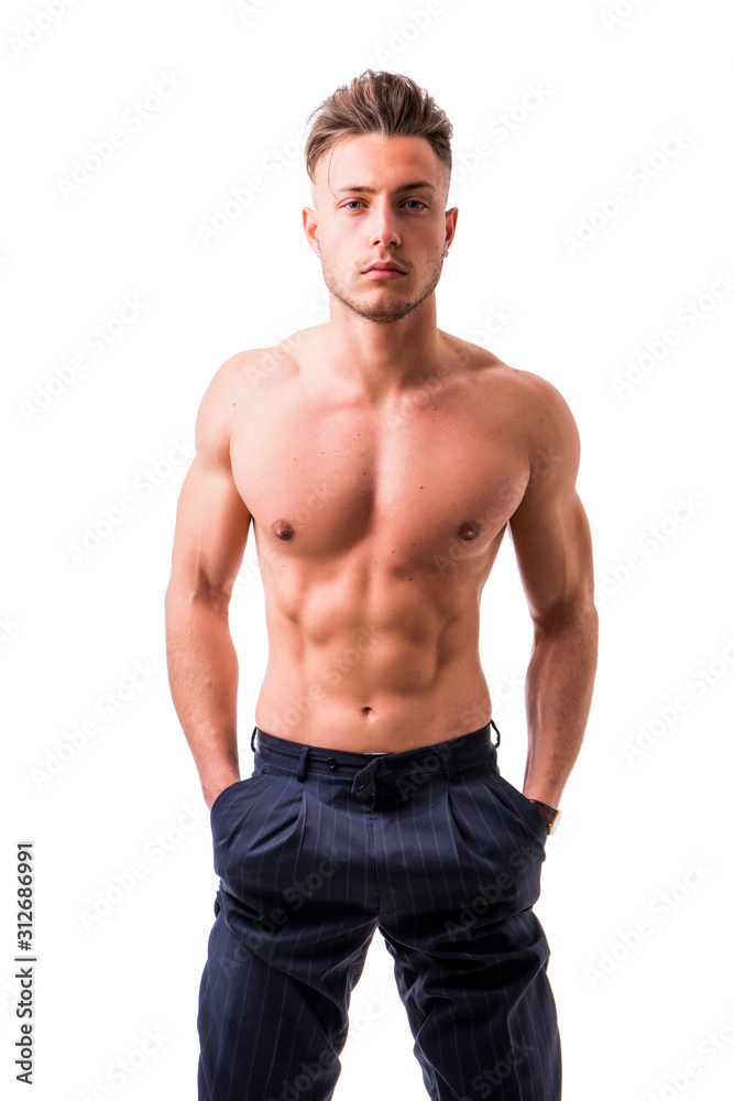 Handsome shirtless athletic young man wearing only pants, with blue eyes, looking at camera in studio shot, isolated on white background