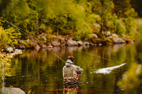 Fisherman using rod fly fishing in river morning standing in water