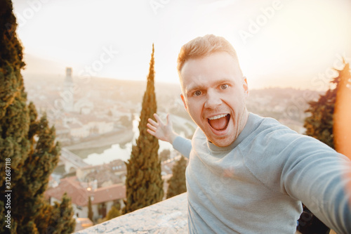 Happy man traveler taking selfie photo on city background Verona Italy sunset. Travel concept photo