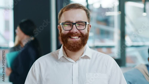 Portrait young man team leader with smiling face posing in office confident business executive ceo looking at camera startup founder training work startup success successful beard close up slow motion photo