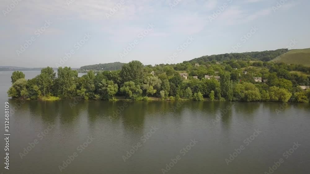 Aerial view of a small village in rural area between green trees on the shore of a big lake. Aerial view of a small village in rural area between green trees on the shore of a big lake.