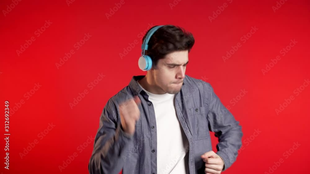 Handsome man with headphones dancing isolated on red background. Party, music, lifestyle, radio and disco concept.