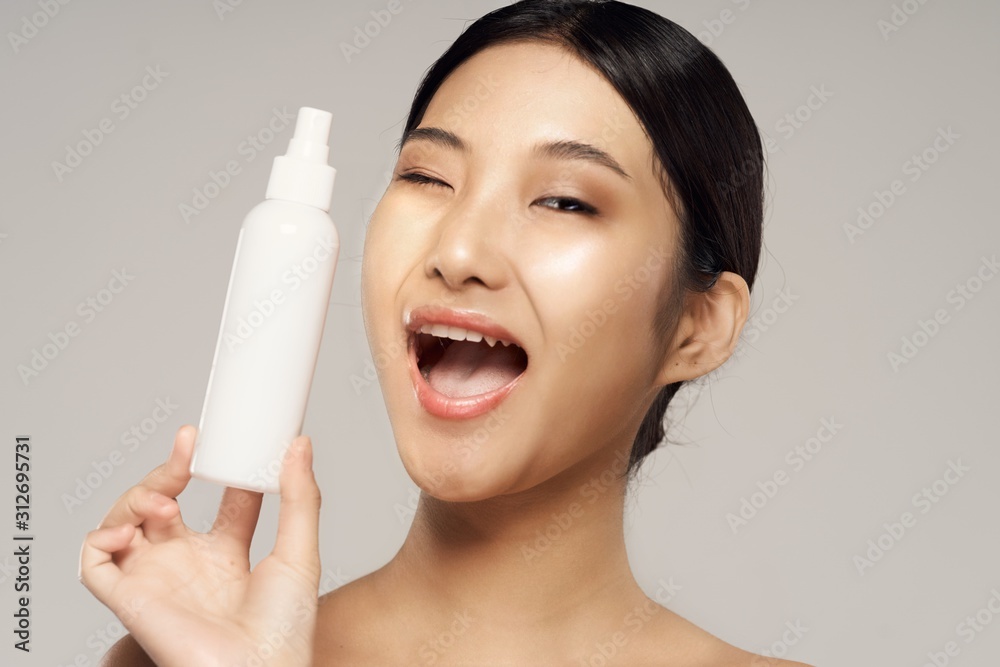 young woman applying cream on her face young woman applying cream on her face
