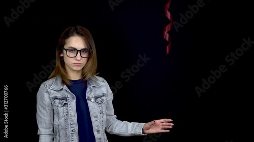 Sad young woman let go of heart-shaped balloon. A sad woman stands with helium balls on a black background. Valentine's Day is the day of all lovers.