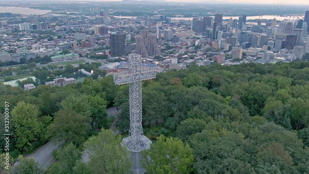 AERIAL: Flying over the cross structure on Mont Royal. In the distance is Montreal city skyline. Quebec, Canada