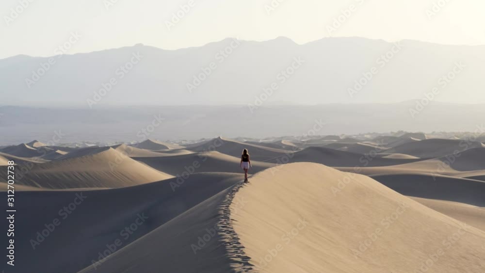 Ultra slow motion shot of woman balancing on sand dune in the desert in Death Valley National Park in California, USA