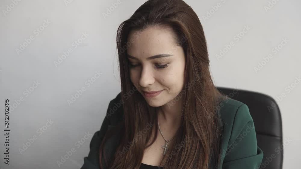 Brunette woman is working in front of a monitor in a office. Business woman working at computer at coworking space. Portrait of happy lady typing at workplace. Female professional working with pc. Brunette woman is working in front of a monitor in a office. Business woman working at computer at coworking space. Portrait of happy lady typing at workplace. Female professional working with pc.