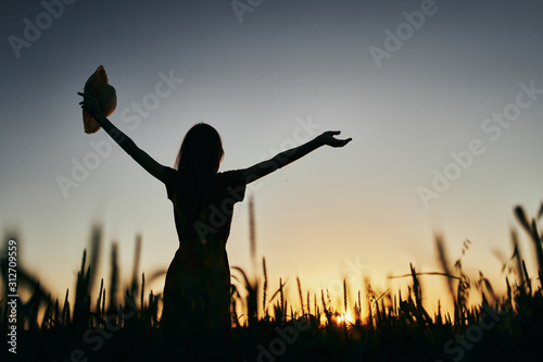 silhouette of young woman with arms raised at sunset