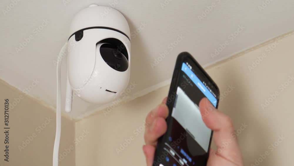 Smartphone controlled home security camera moving filming around. Smart home surveillance system remotely operated. IP Internet CCTV cameras are a growing trend in a connected house.
