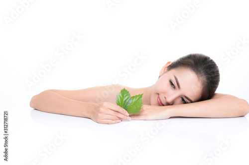 Close-up studio shot  Beautiful young woman with clean fresh skin holding green leaves. Proposing a product. Gestures for advertisement isolated on white background.