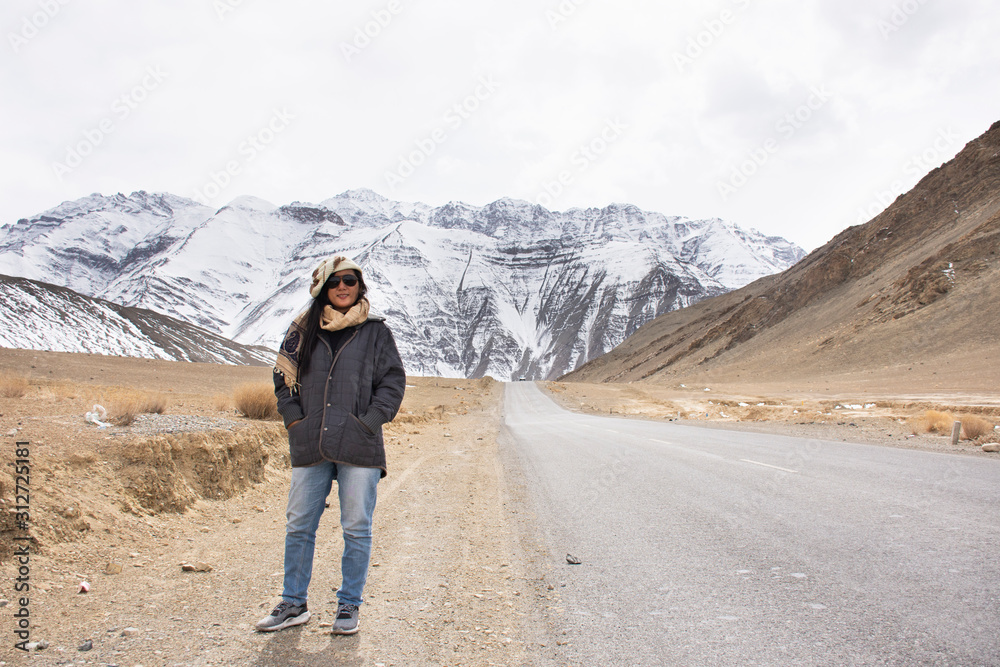 Travelers thai woman travel visit and posing for take photo with landscape high range mountain on Srinagar Leh Ladakh highway at Leh Ladakh village in Jammu and Kashmir, India at winter season