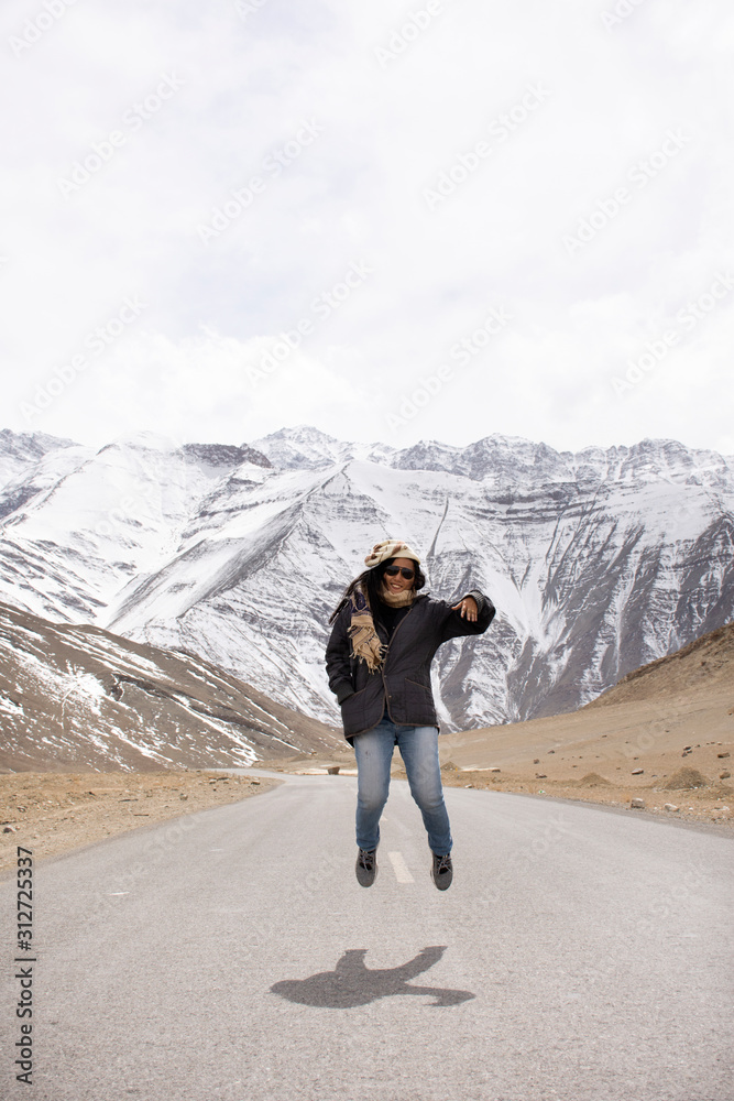 Travelers thai woman travel visit and jumping for take photo with landscape high range mountain on Srinagar Leh Ladakh highway at Leh Ladakh village in Jammu and Kashmir, India at winter season