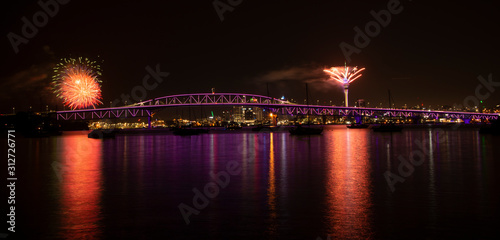 Auckland fireworks for New Year celebration with Harbor Bridge illuminated in purple