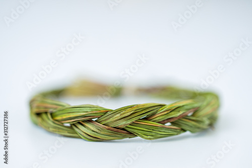 Close up of middle of green fresh sweetgrass braid tied in a circle isolated on white background